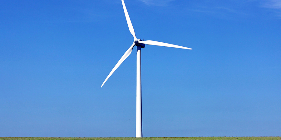 A white wind turbine against a clear blue sky