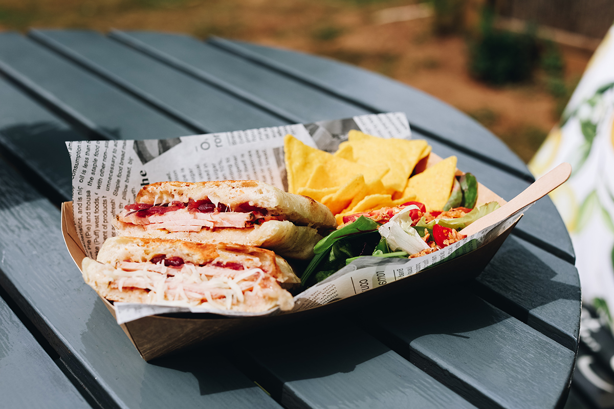One of Natural Rise' paninis A close-up photograph of a panini in a serving tray on an outdoor table on a sunny day, crafted by Natural Rise at How Hill