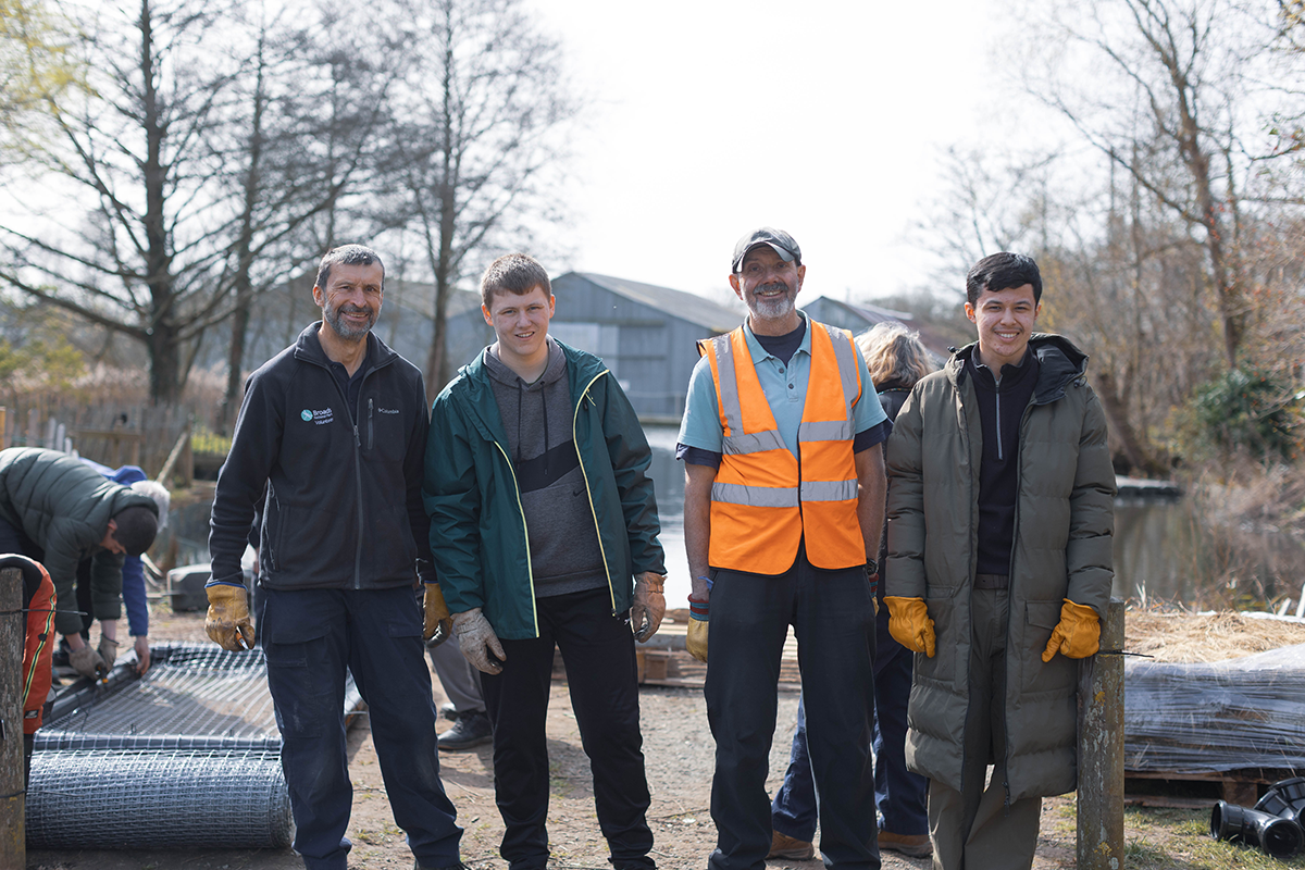 Volunteers at Hoveton Riverside Park Volunteers and staff at a riverside conservation project, standing beside wire mesh and habitat management materials.