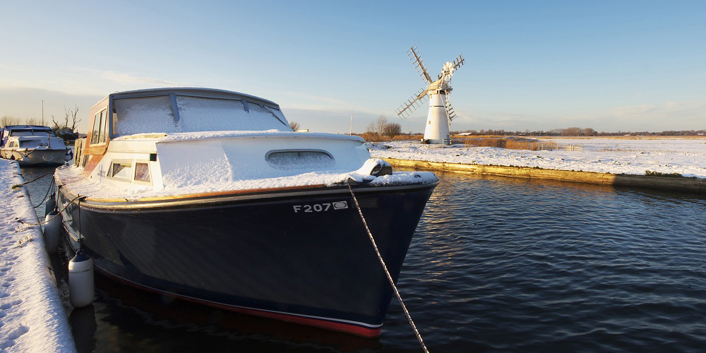 boat moored up in winter with a mill in the distance