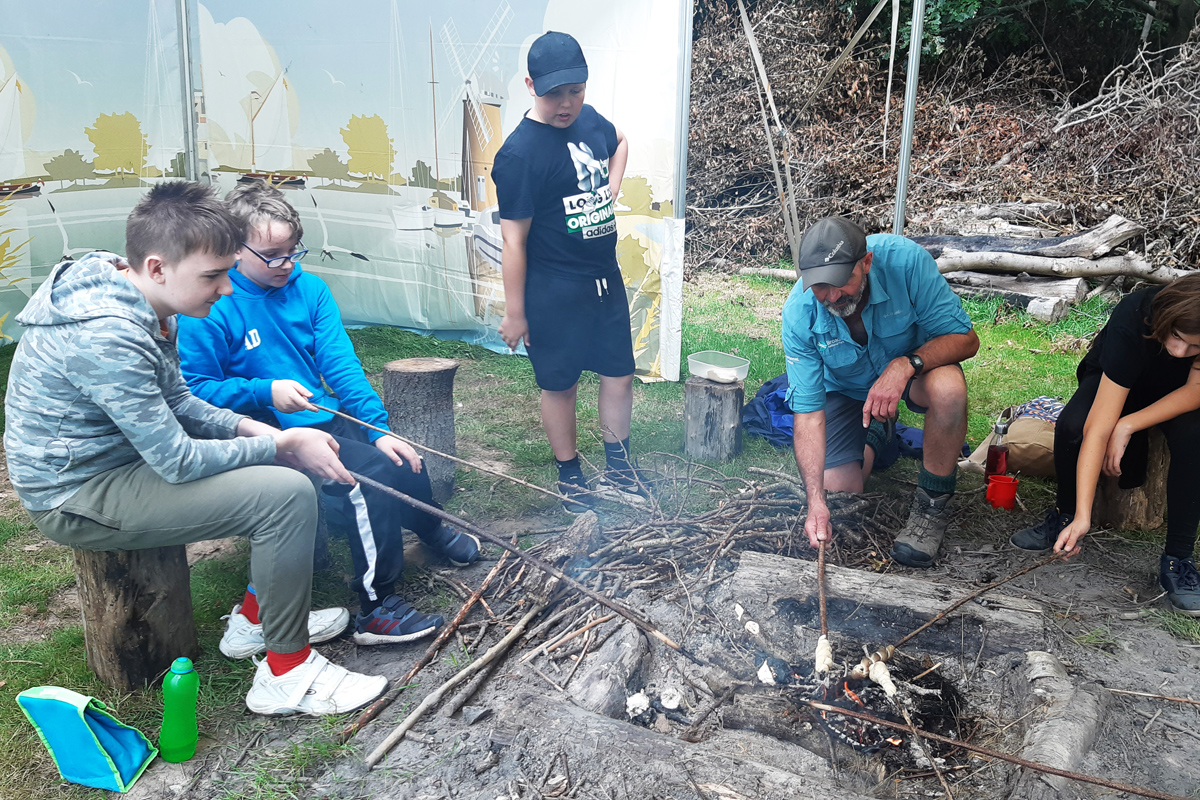 Nick with a group of children demonstrating bushcraft cooking skills