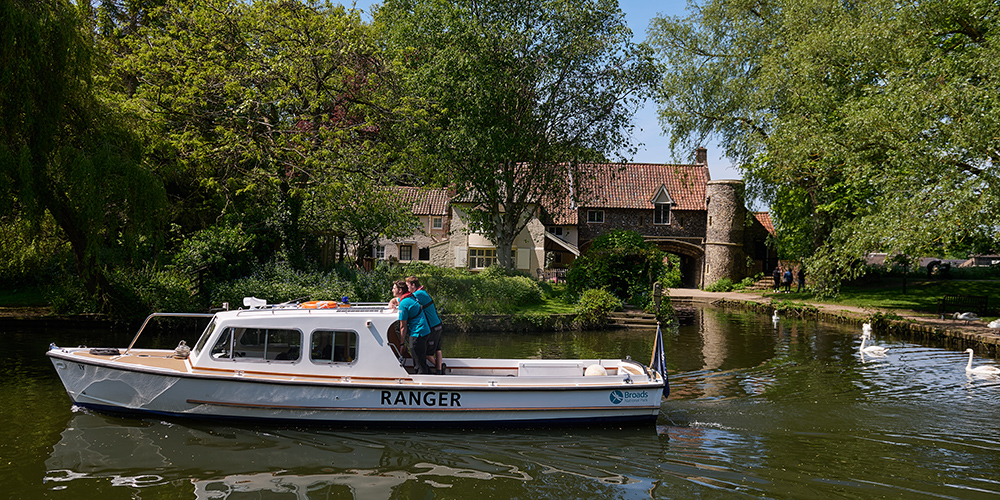 Two Rangers travelling on a white patrol boat on the river wensum