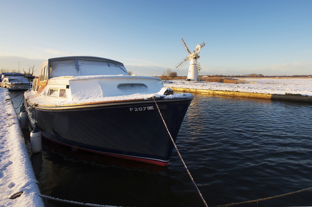 boat moored up in winter with a mill in the distance